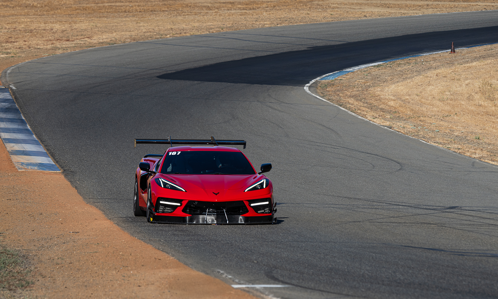 Red C8 Corvette with aero kit entering a corner at Thunderhill East